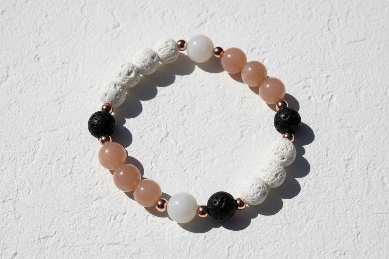 Beaded bracelet with white, pink, and black beads on a light grey surface.