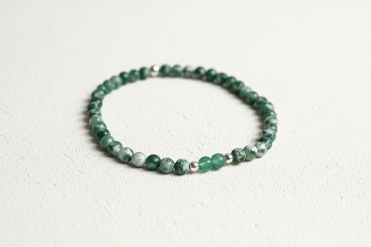 Green beaded bracelet on a textured fabric surface.