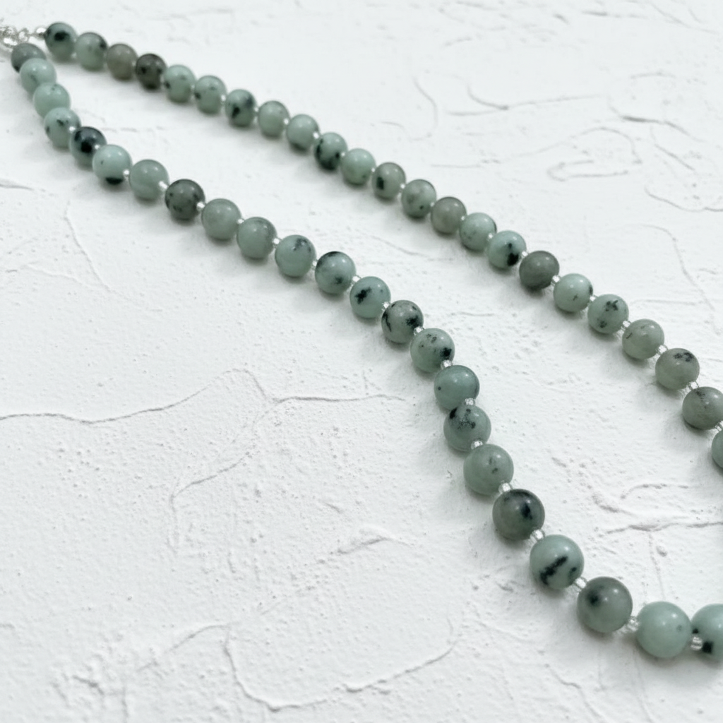 Necklace with pale beads on a light beige fabric background.