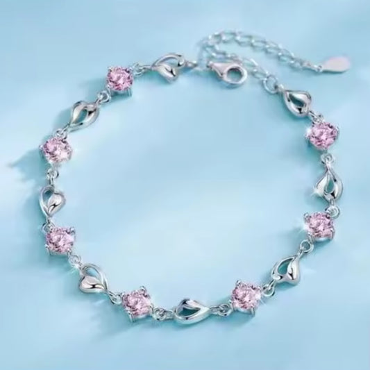 Silver bracelet with pink crystals and silver heart-shaped links on a light blue background