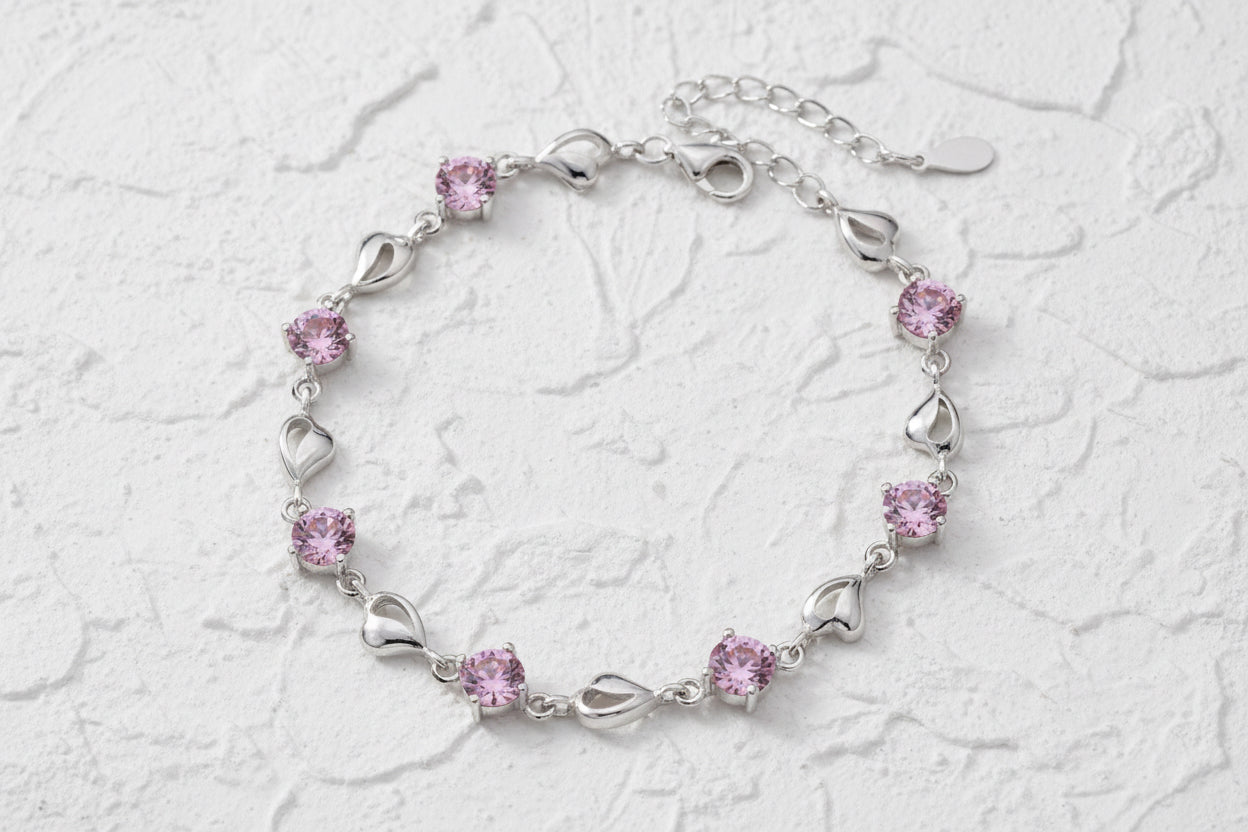 Silver bracelet with pink crystals and silver heart-shaped links on a light blue background