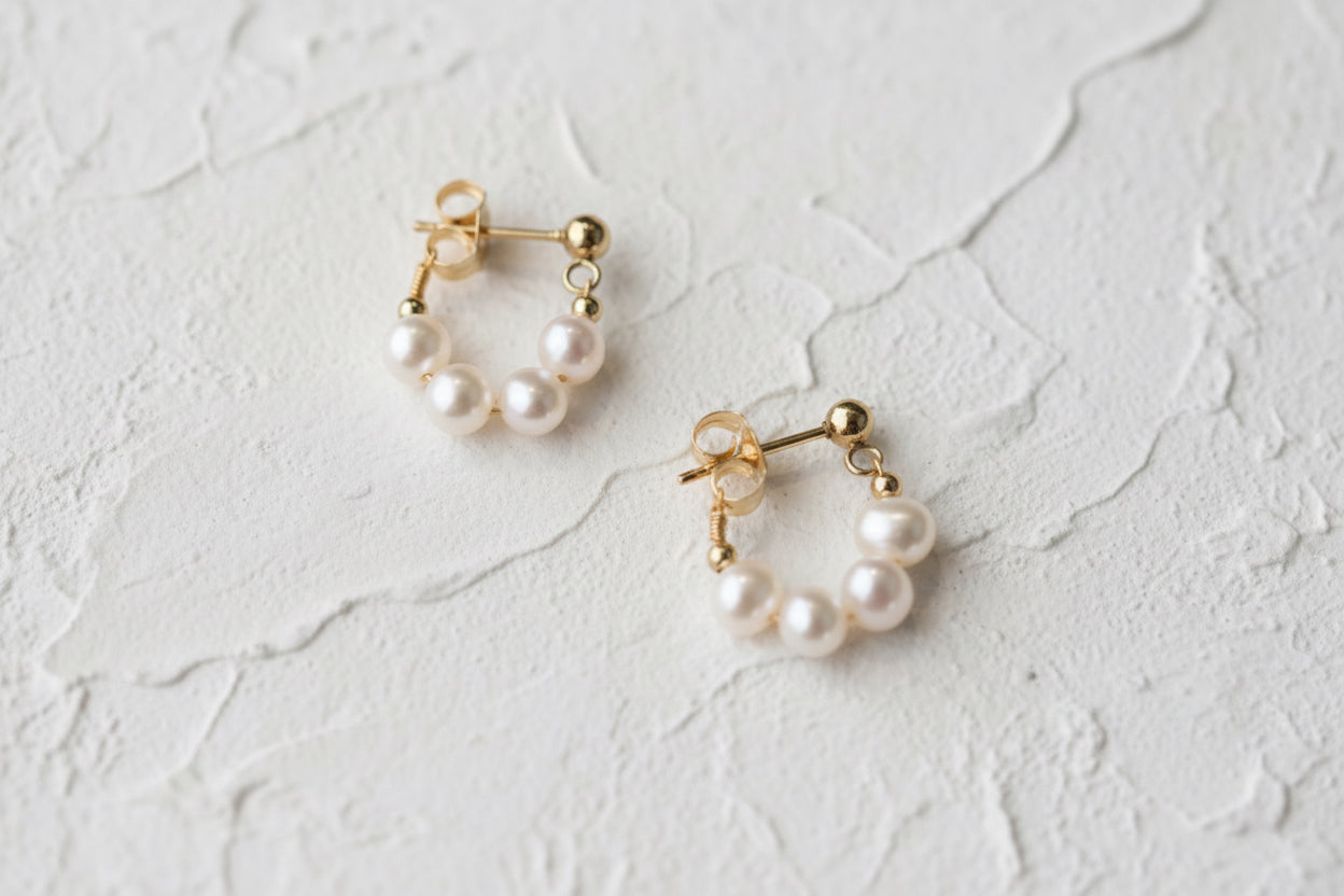 Pair of pearl earrings with gold accents on a light background.