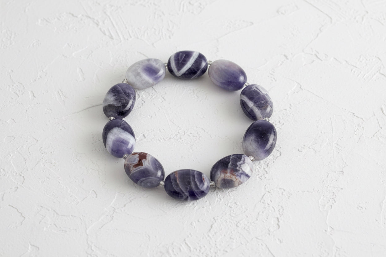 Purple amethyst beaded bracelet on a light grey background.