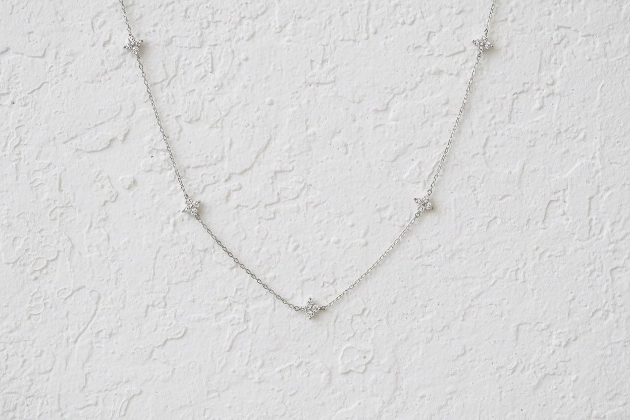 Silver necklace necklace with dainty crystal clovers on a dark blue background