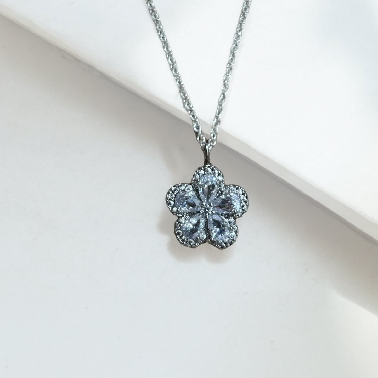 Flower shaped crystal pendant on a silver chain against a light background