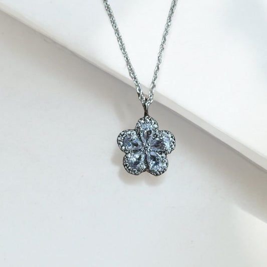 Flower shaped crystal pendant on a silver chain against a light background
