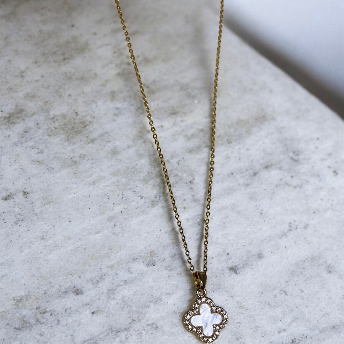 Necklace with a clover pendant on a gold coloured chain.