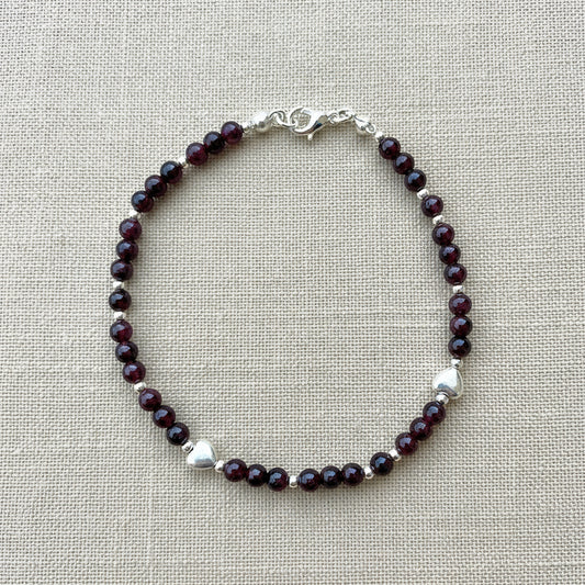 A deep red garnet and silver beaded bracelet.