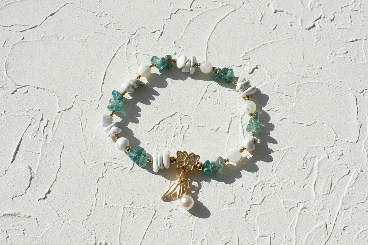 Bracelet with green and white beads and a gold charm on a beige background.