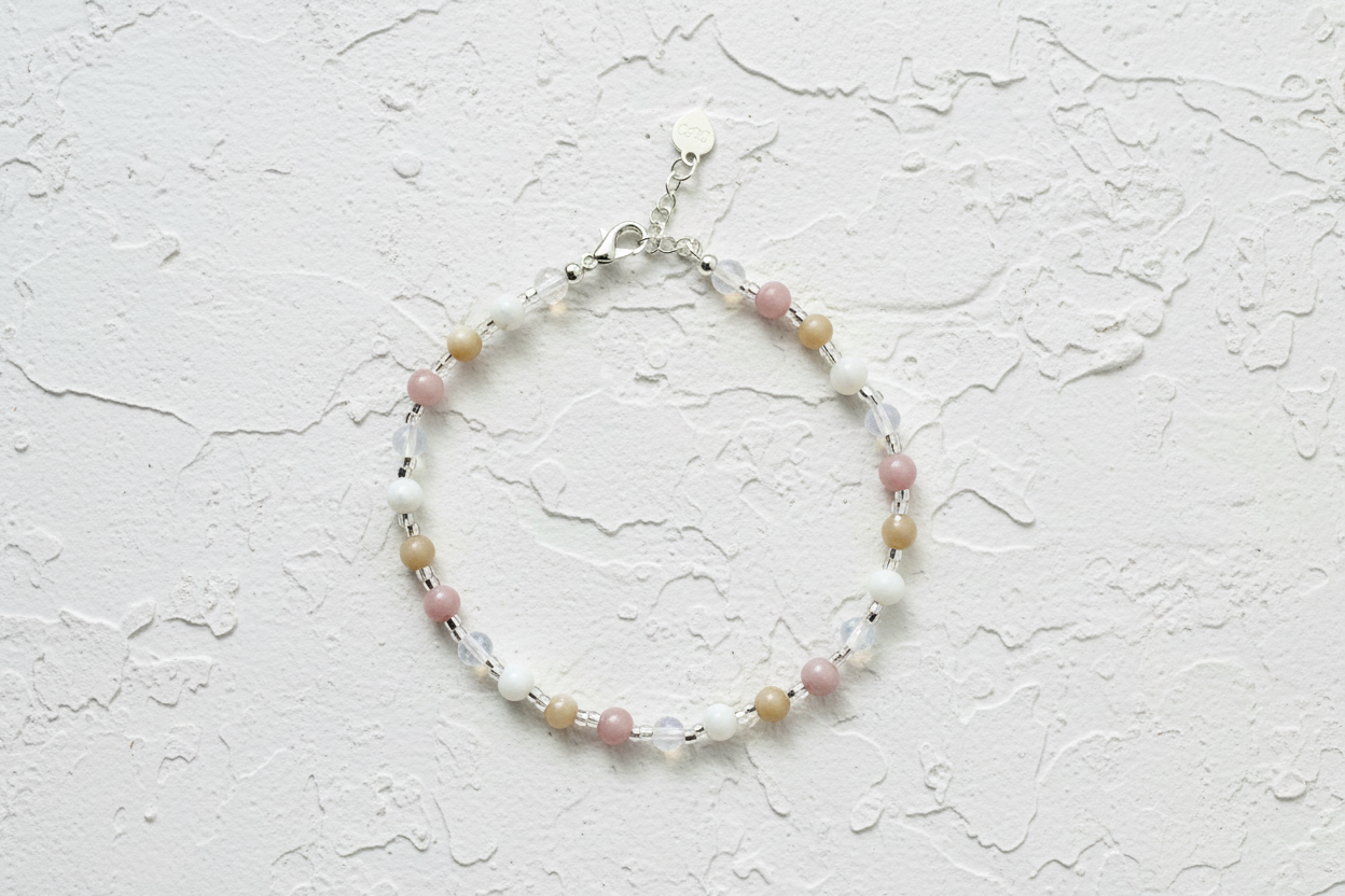 Beaded bracelet with pink and white stones on a beige background.