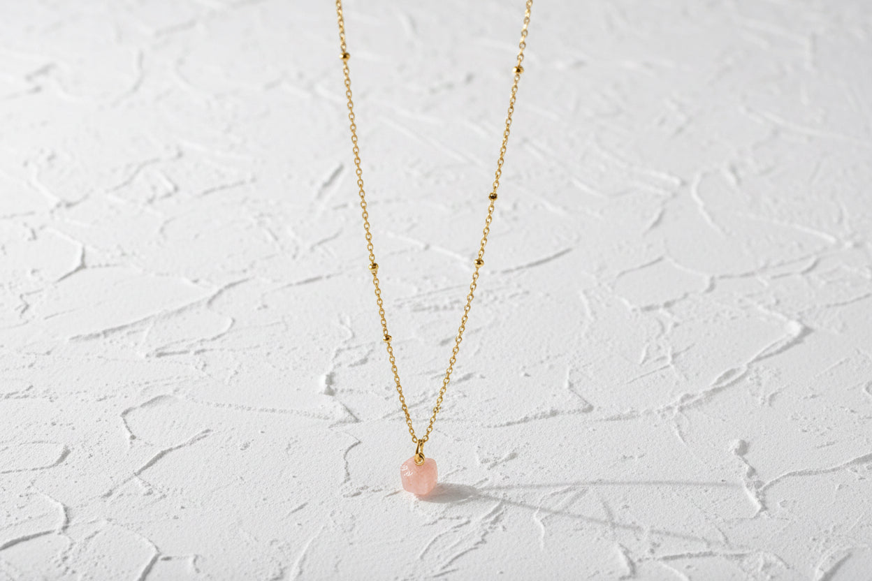 Pink opal raw crystal pendant on a gold chain.