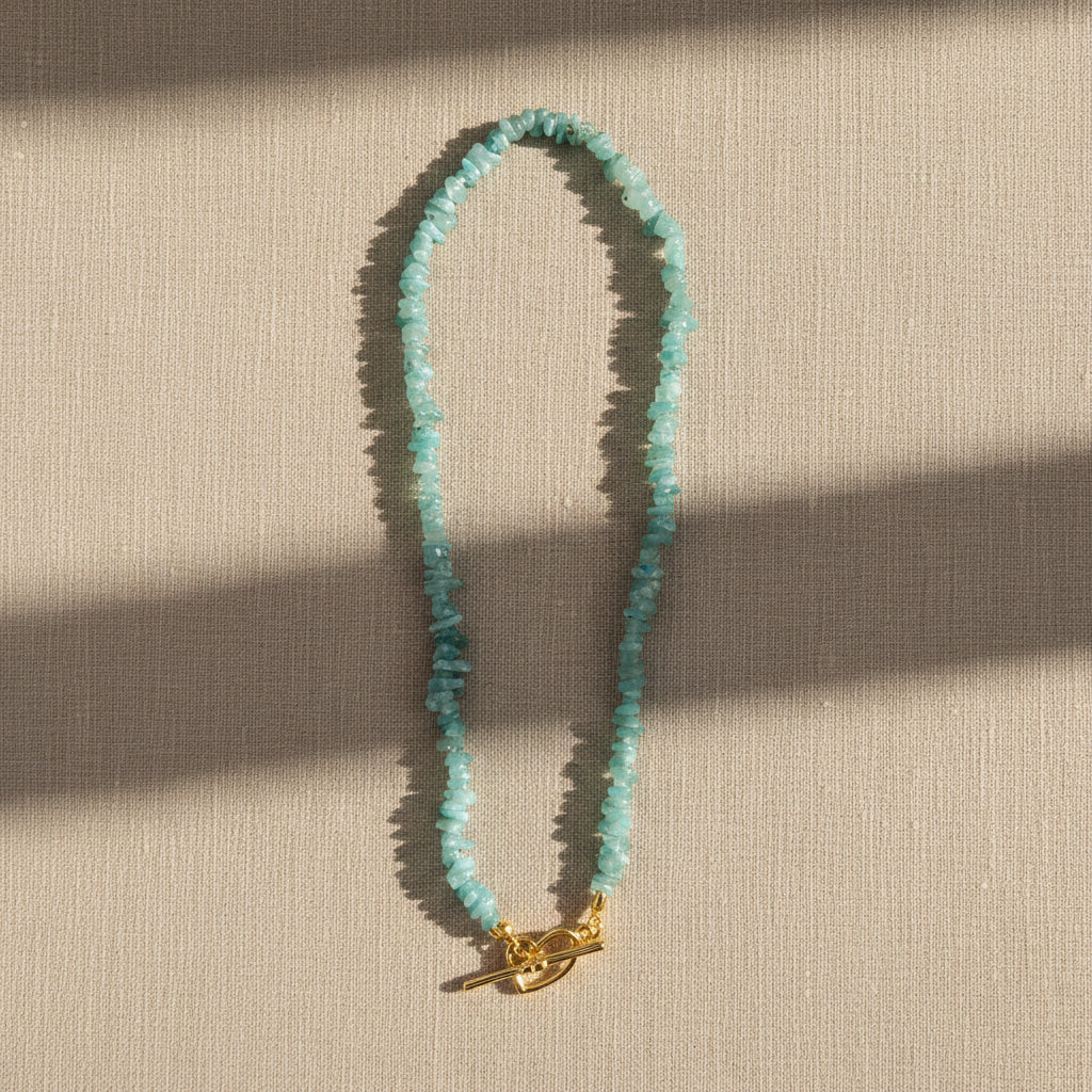 A topaz blue crystal chip necklace displayed on a linen surface.