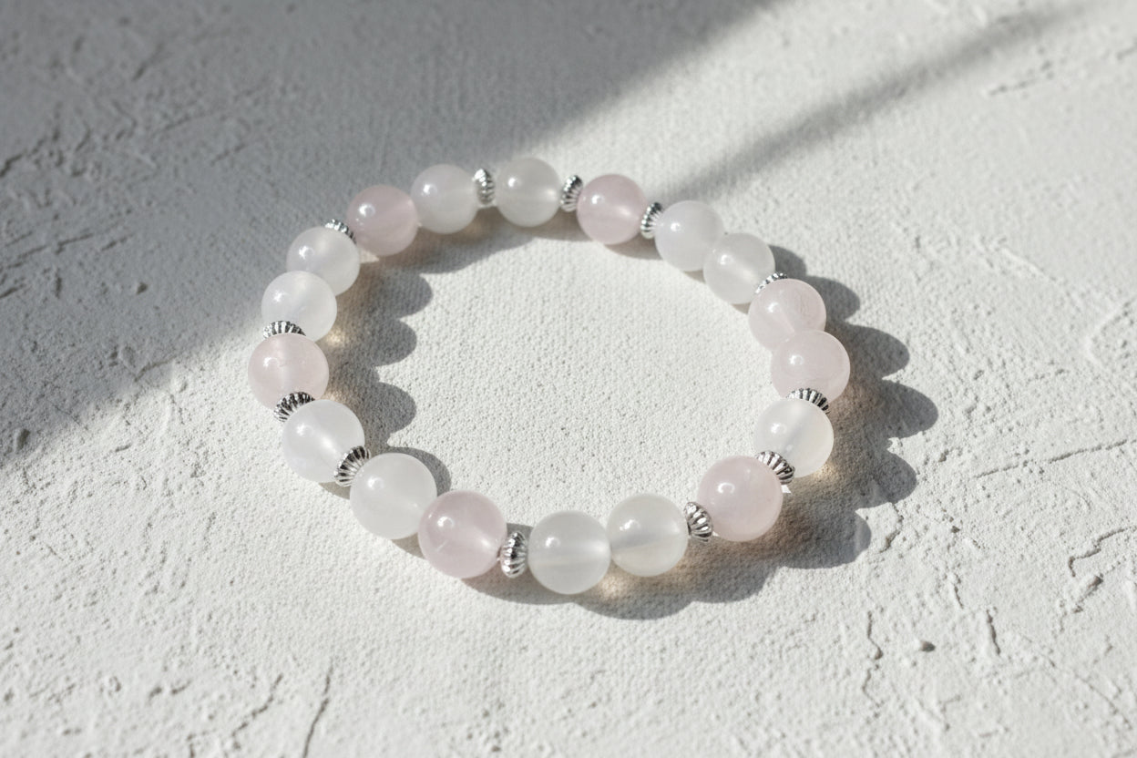Beaded bracelet with pink opaque stones on a grey surface.