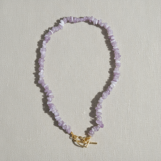Purple crystal chip necklace with a gold toggle clasp on a light background.