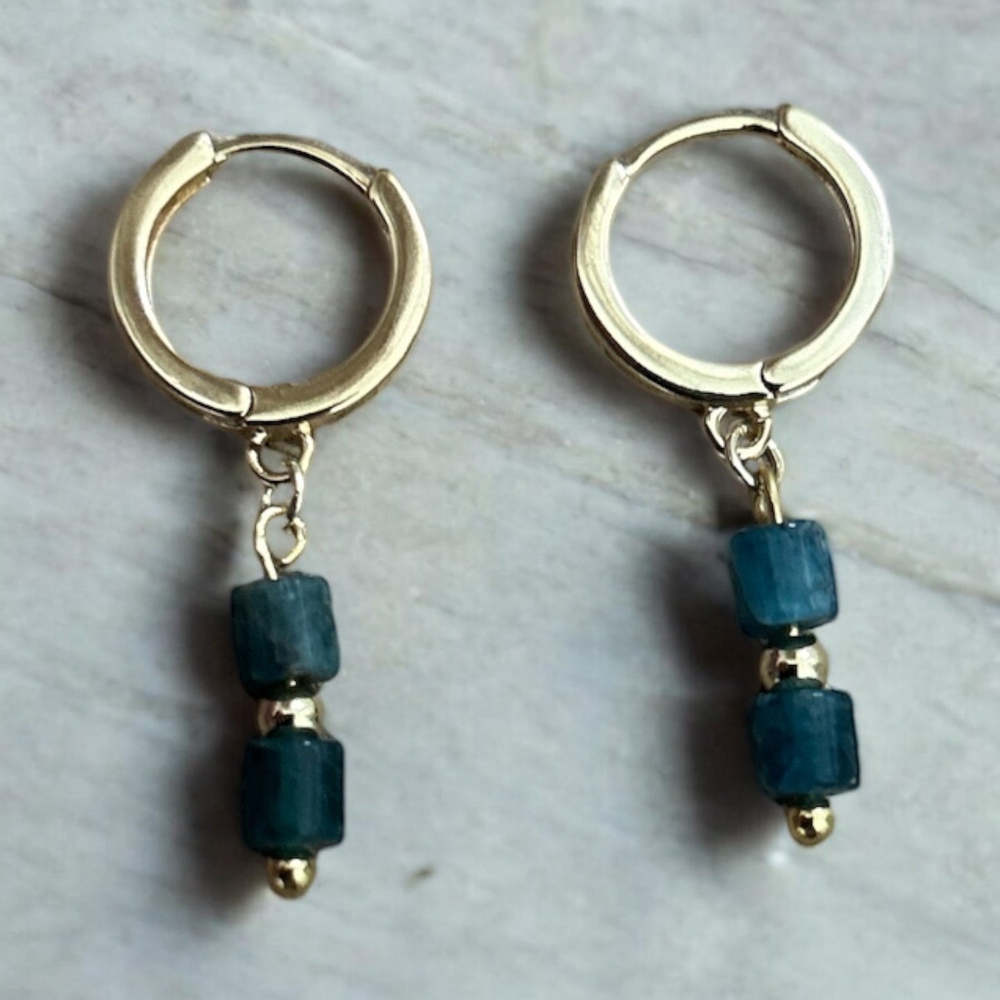 Gold huggie earrings with blue crystal drop gems.