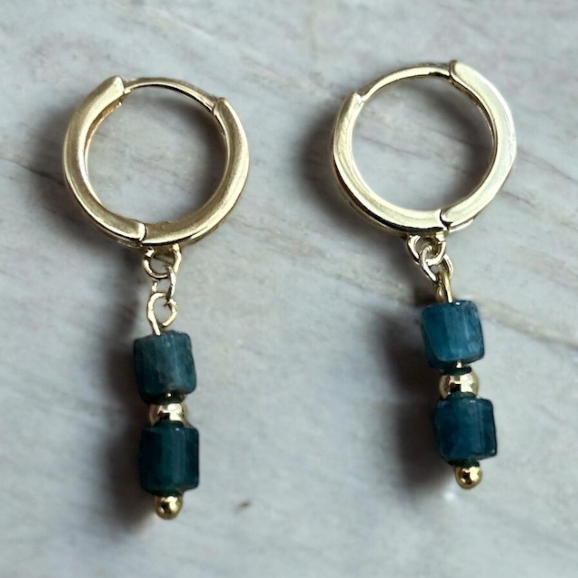 Gold huggie earrings with blue crystal drop gems.