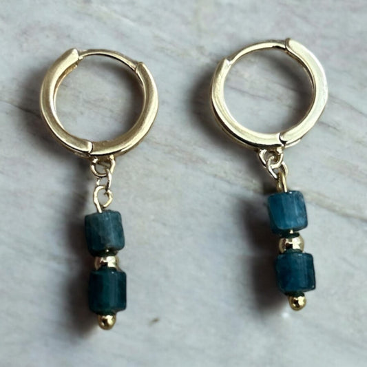 Gold huggie earrings with blue crystal drop gems.