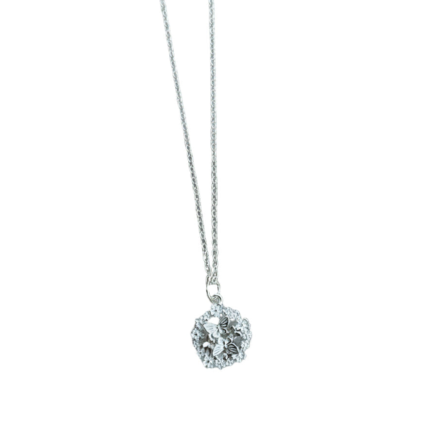 Silver necklace with a round pendant and butterflies on a white background.
