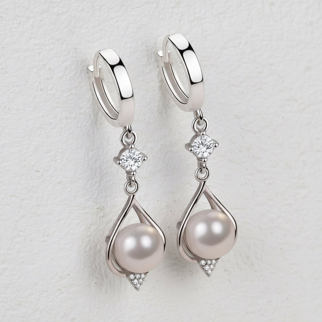 Silver huggie hoops with pearl and crystal drop on a soft grey background.