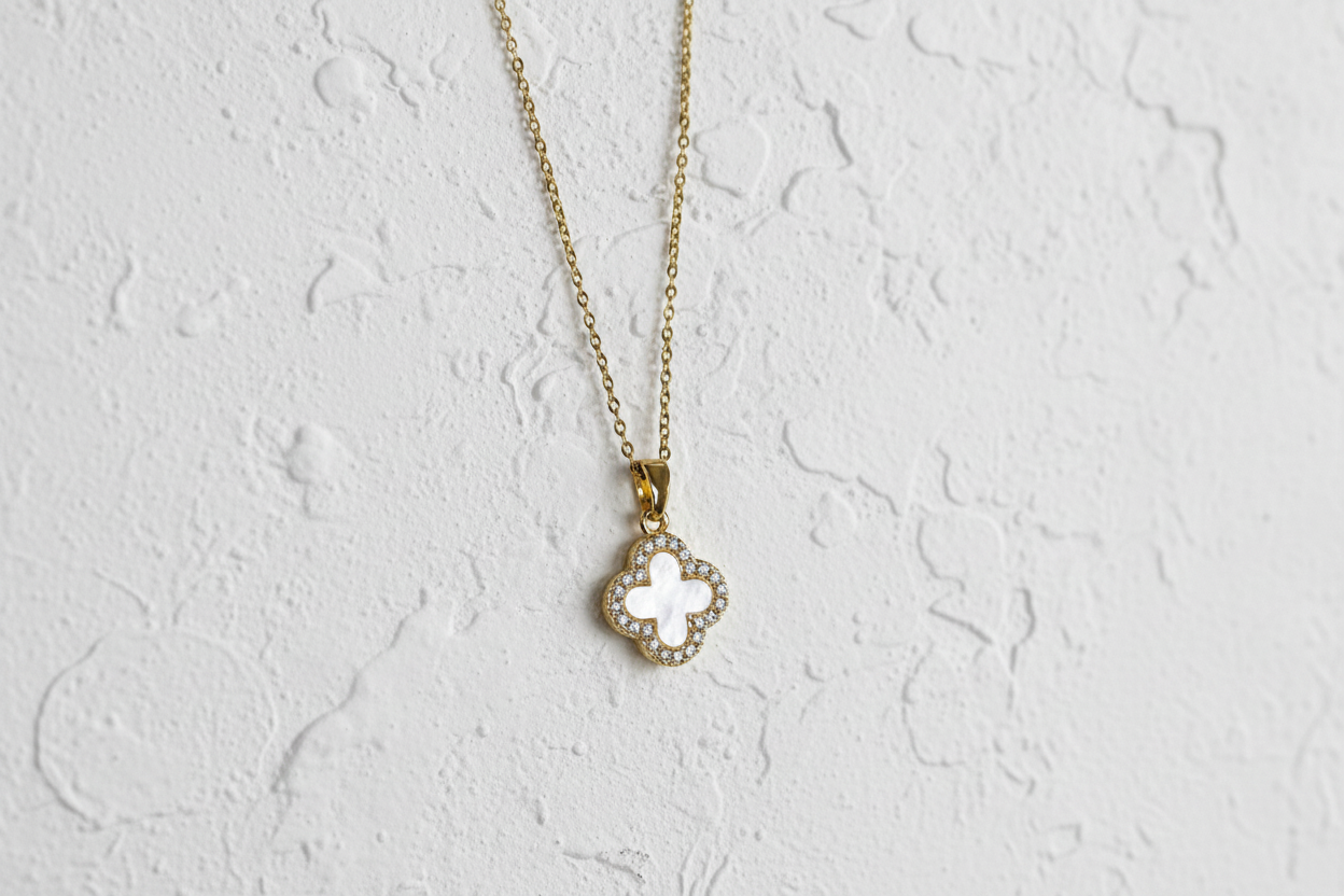 Necklace with a clover-shaped pendant on a light grey background.