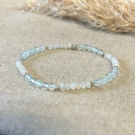 Beaded blue, pink and silver bracelet on a textured fabric surface.