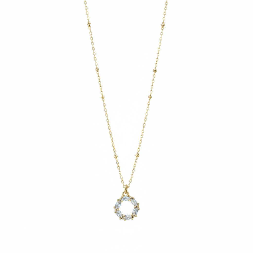 Gold necklace with a circular pendant on a grey background.