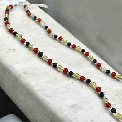 Beaded necklace with red, black, and yellow beads on a white surface.