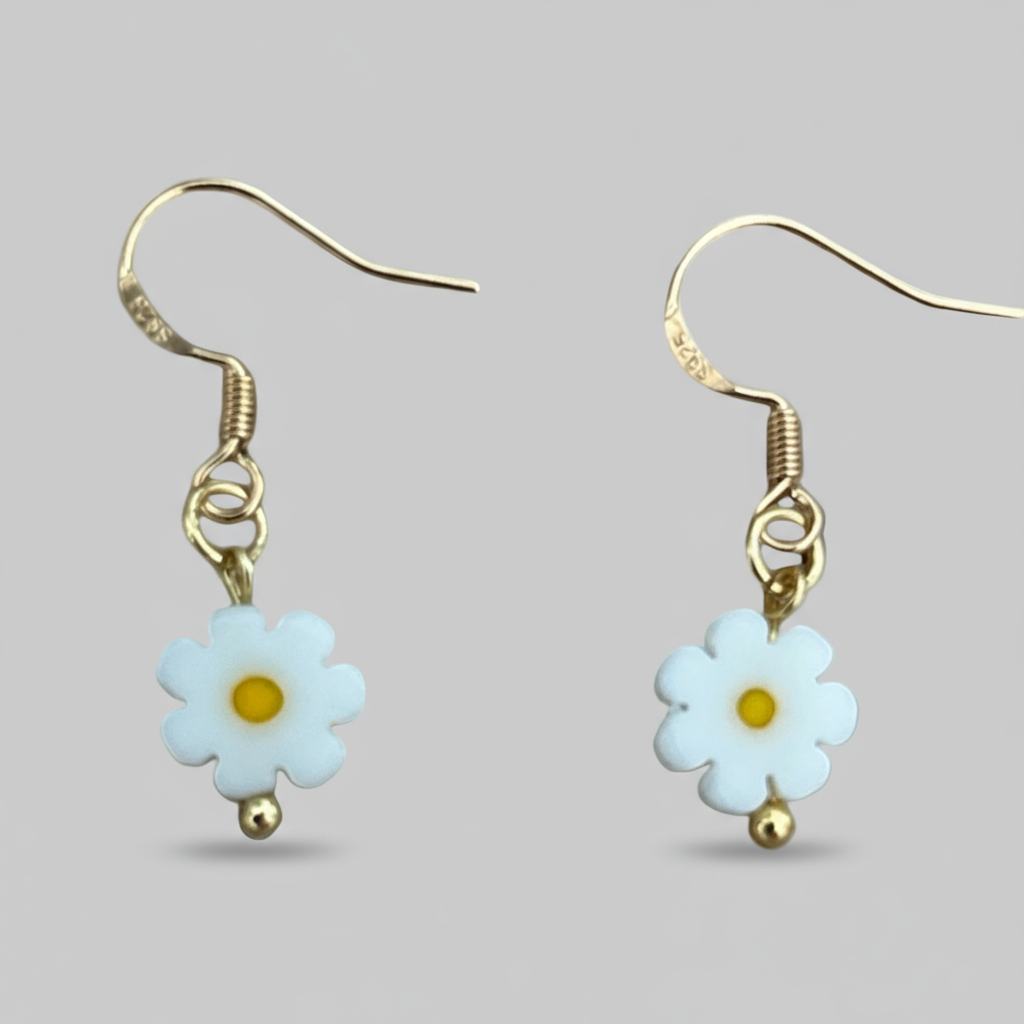 Pair of daisy flower earrings with gold accents on a light gray background