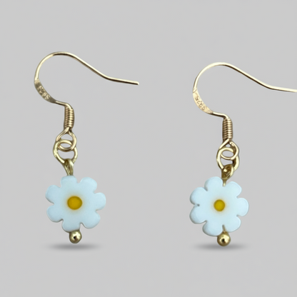 Pair of daisy flower earrings with gold accents on a light gray background