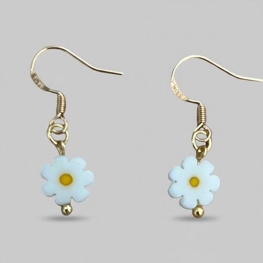 Pair of daisy flower earrings with gold accents on a light gray background
