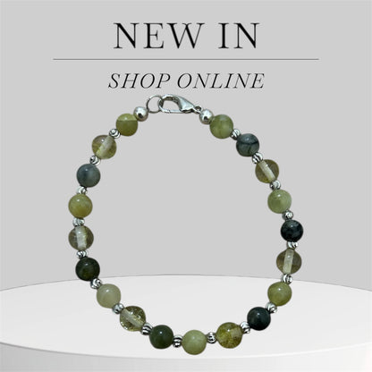 Beaded bracelet with green and black stones on a light grey background.