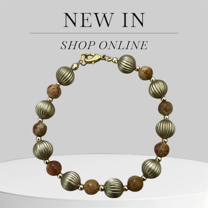 Bracelet with gold and brown beads on a light gray background.