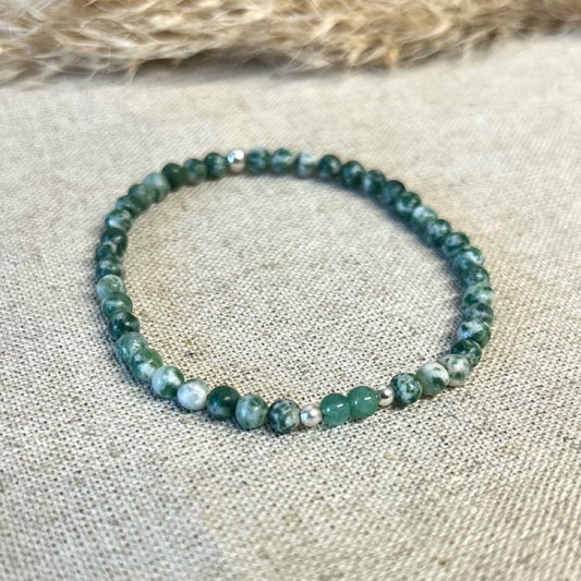 Green beaded bracelet on a textured fabric surface.
