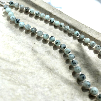 Necklace with blue and grey speckled beads on a textured surface.