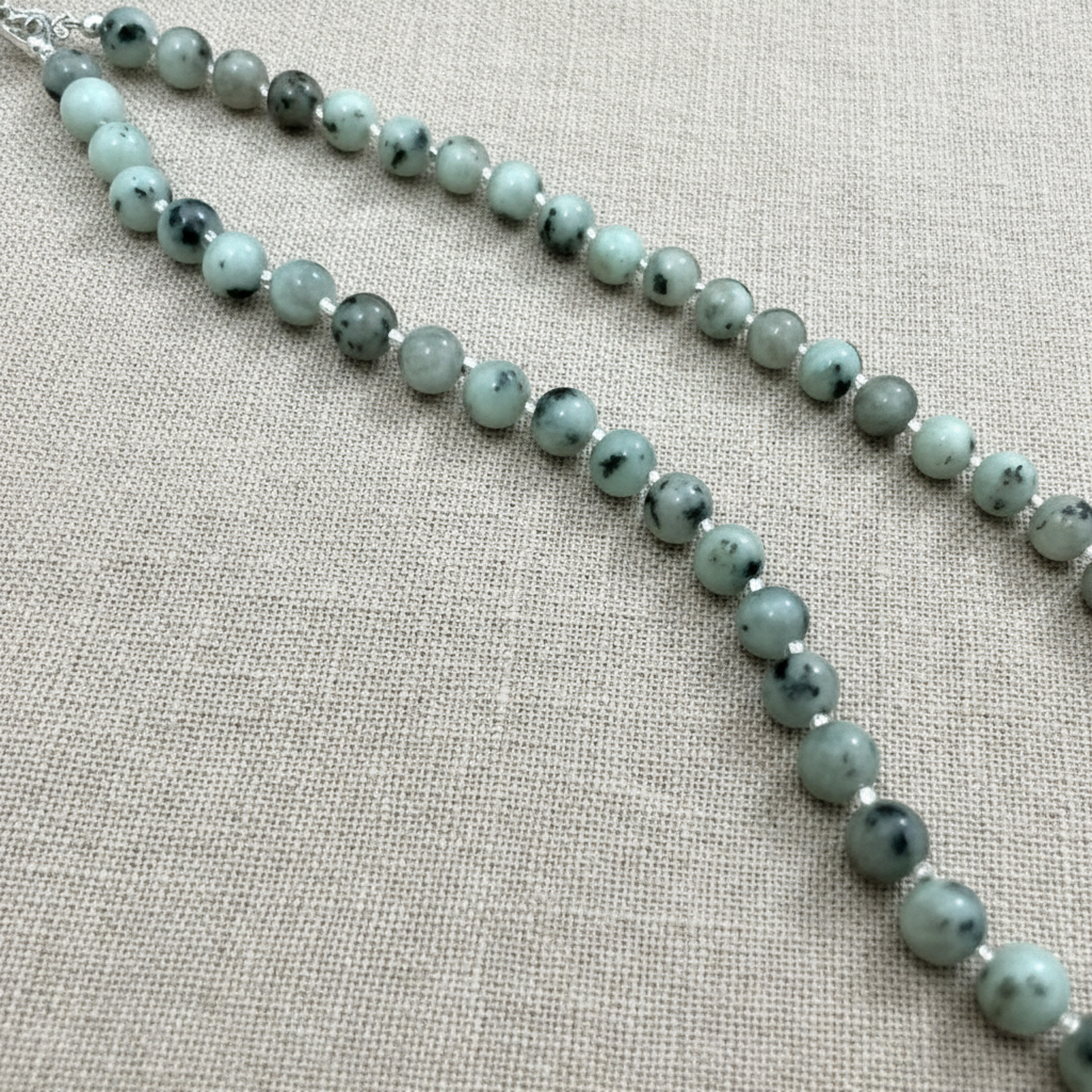 Necklace with pale beads on a light beige fabric background.