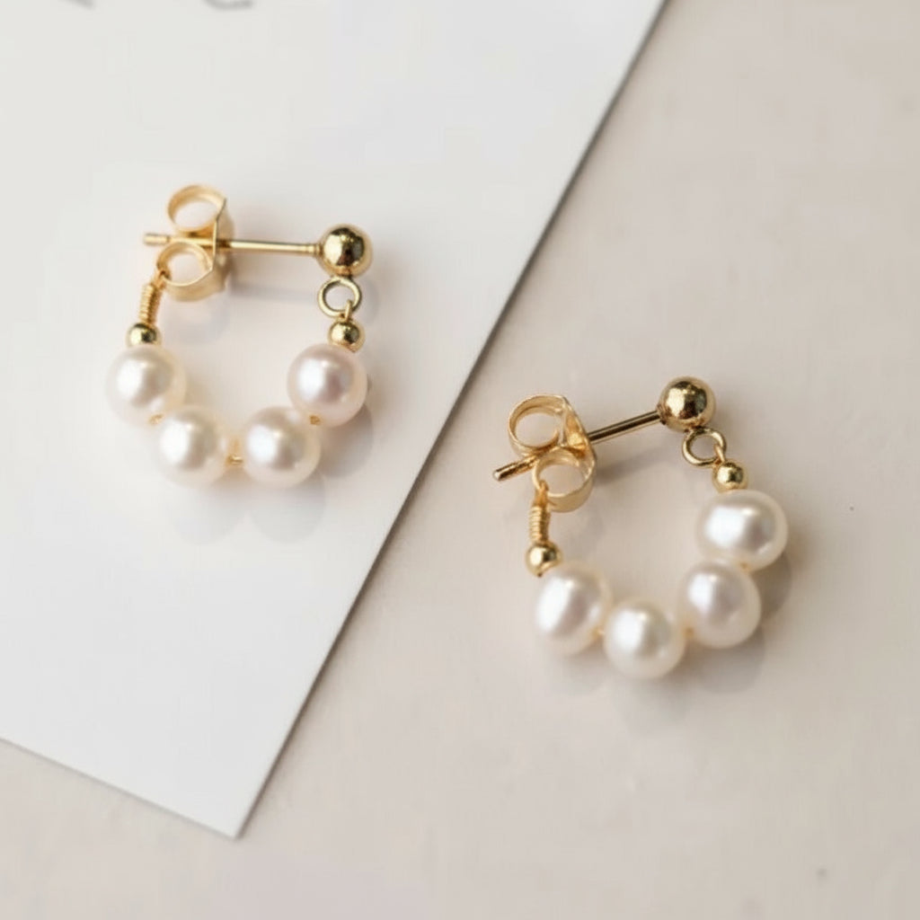 Pair of pearl earrings with gold accents on a light background.