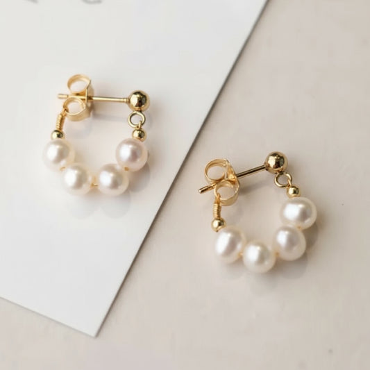 Pair of pearl earrings with gold accents on a light background.