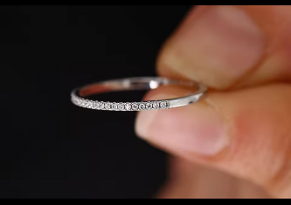 Silver ring held in a hand with a black background.