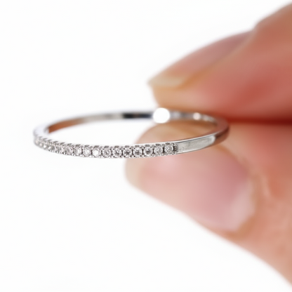 Silver ring with small diamonds held against a white background.