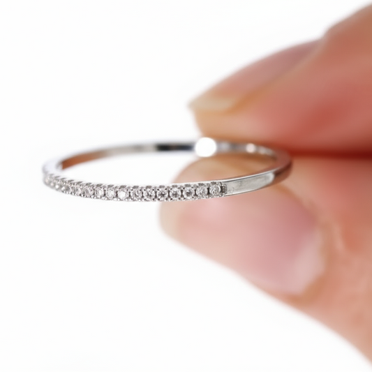 Silver ring with small diamonds held against a white background.