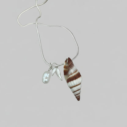 A seashell necklace with a fresh water pearl and two 925 sterling silver charms, one of which is a pearl.
