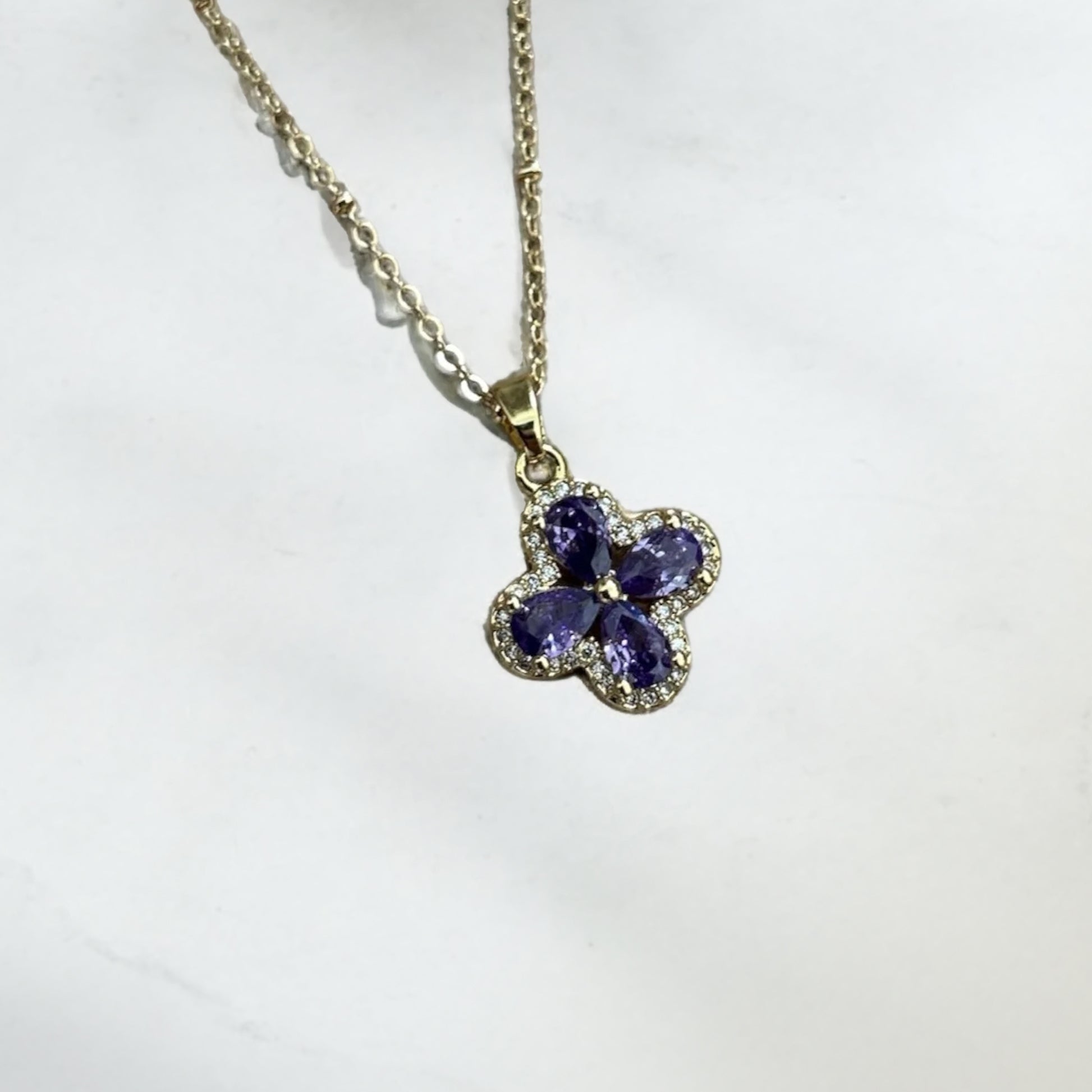 Necklace with a floral pendant featuring purple stones on a white background