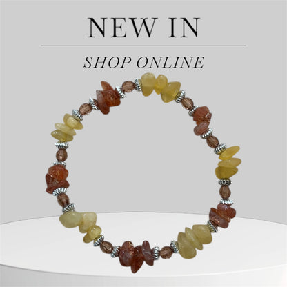 Orange and yellow crystal bracelet with 'New In' and 'Shop Online' text on a light grey background.