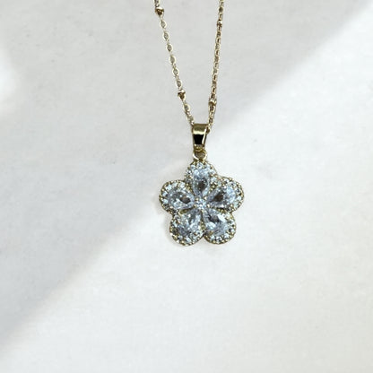 Flower-shaped pendant on a gold chain against a white background