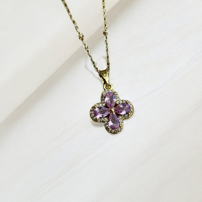 Gold necklace with a pink flower-shaped pendant on a light background