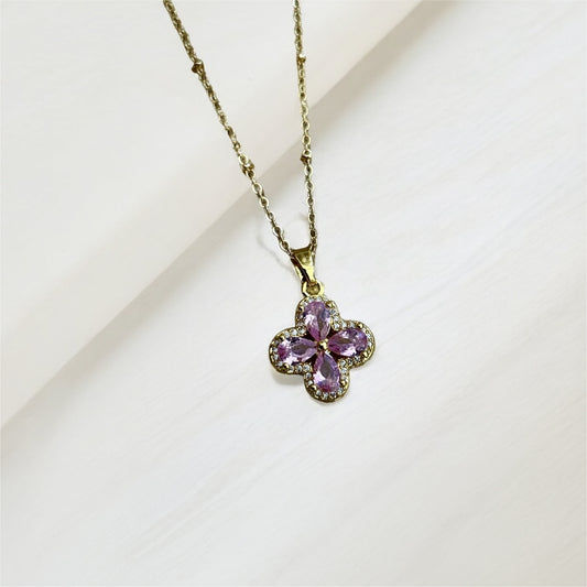 Gold necklace with a pink flower-shaped pendant on a light background