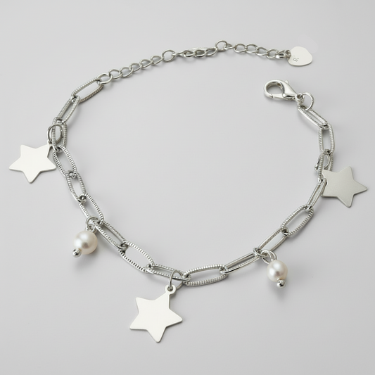 Silver bracelet with star and pearl charms on a light grey background.