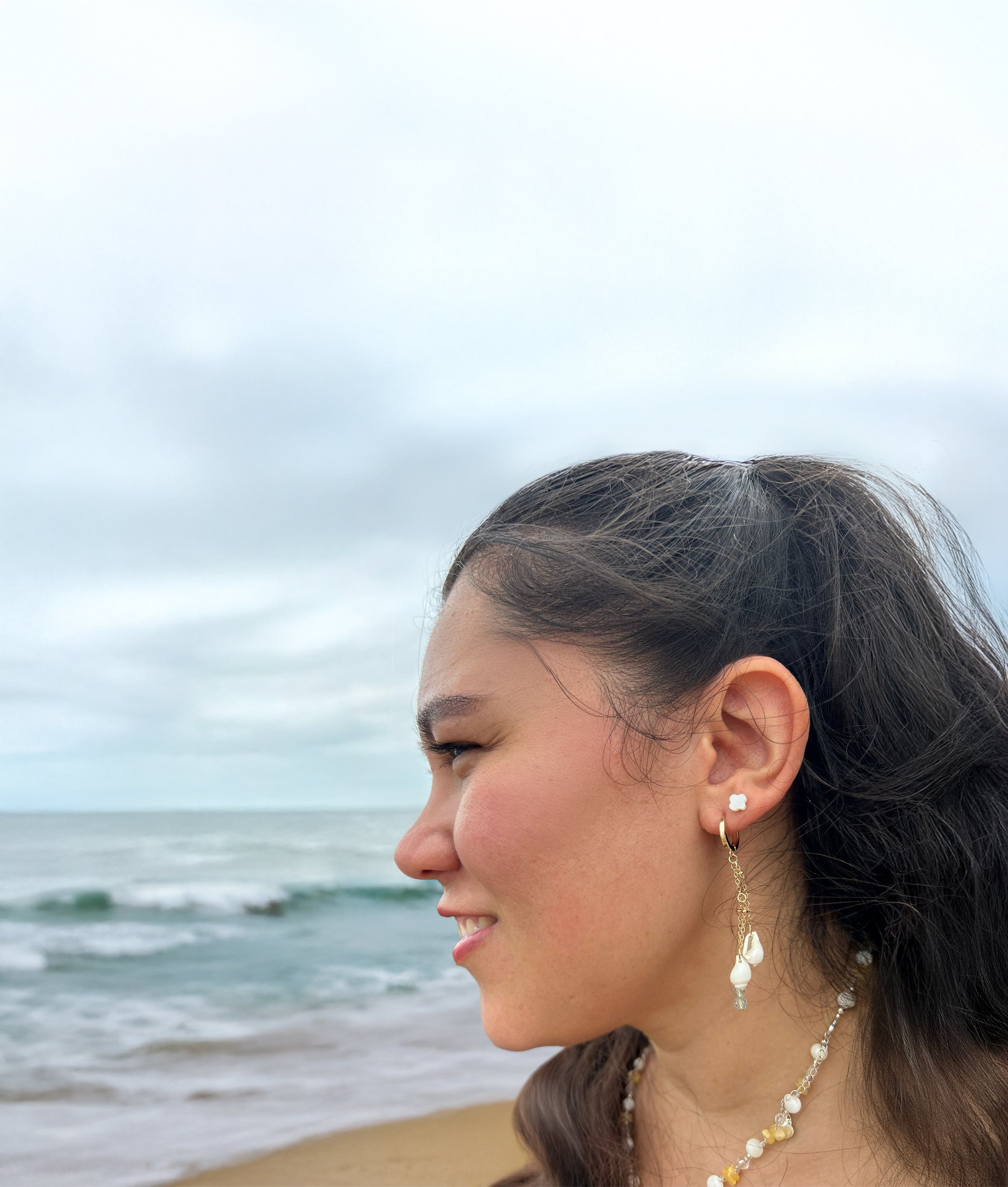 Woman with earrings and a necklace standing on a beach