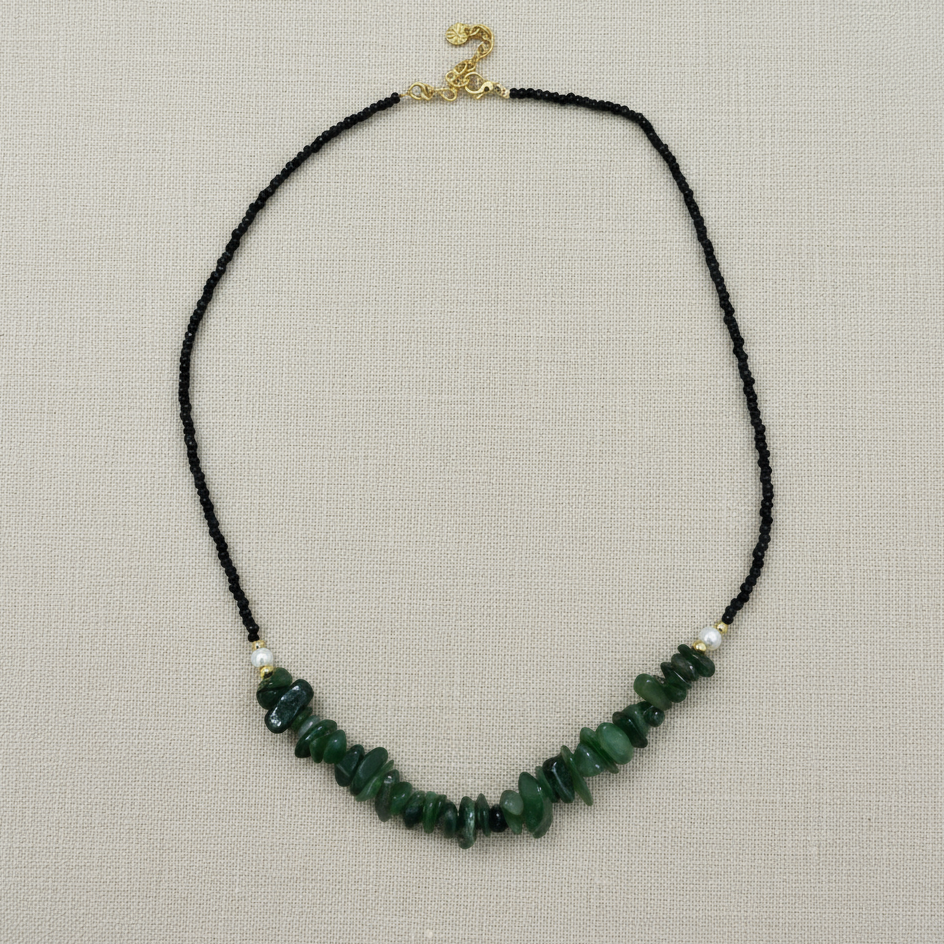 Necklace with green beads on a black cord against a white background