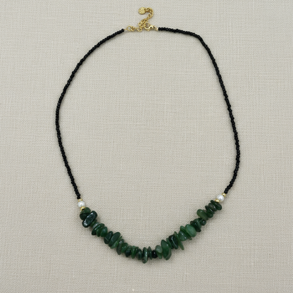 Necklace with green beads on a black cord against a white background